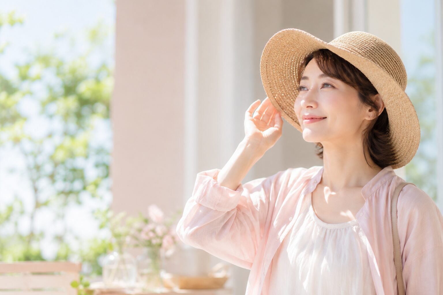 つばの広い帽子で夏の日ざしを心地よく楽しむ50代女性